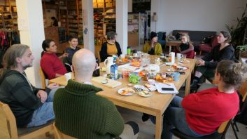 Teilnehmer:innen des Netzwerktreffens sitzen um einen Tisch in der KlimaWerkStadt und frühstücken gemeinsam. 